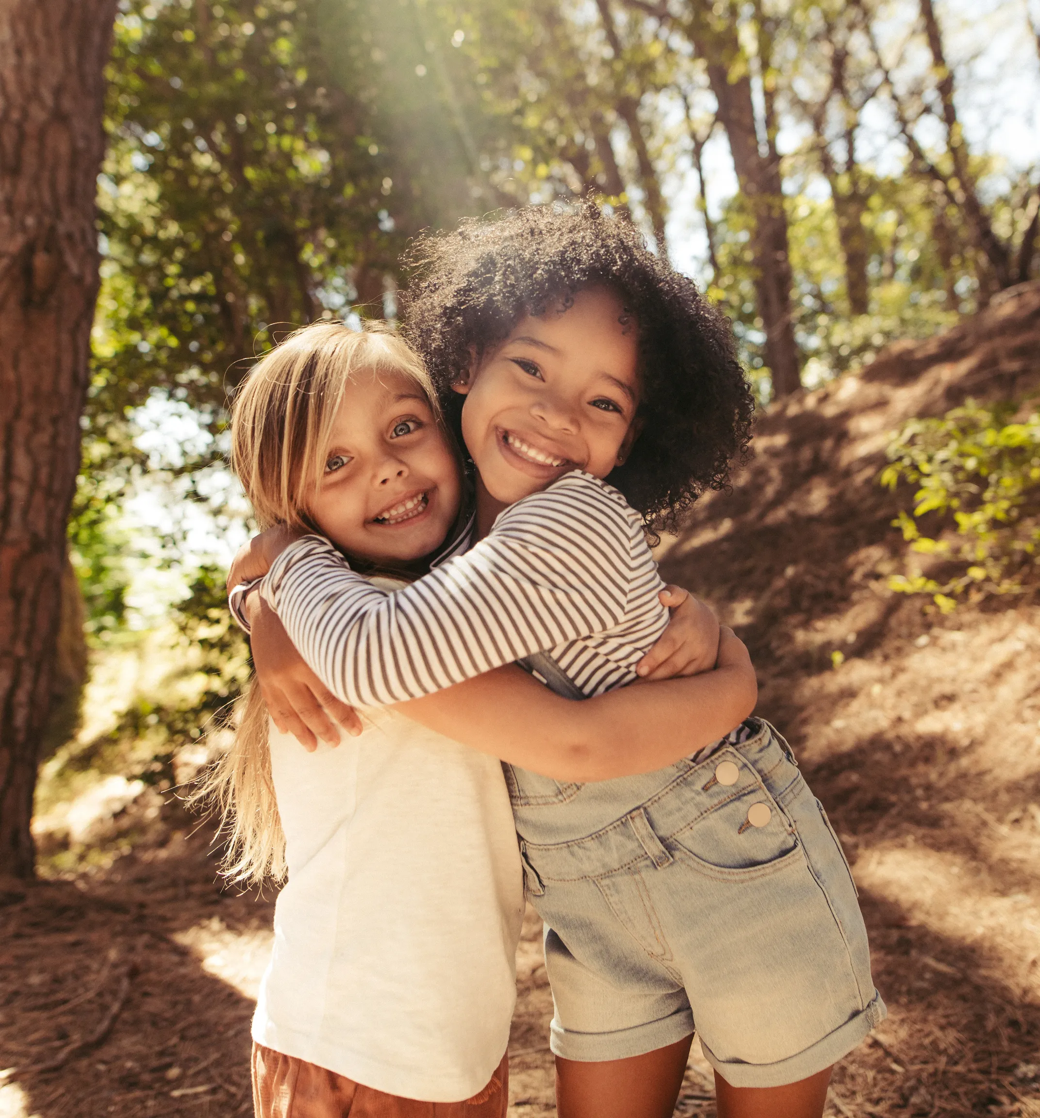 Two friends hug while smiling cheerfully at the camera.